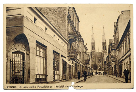 Pocztówka przedstawiająca ulicę Marszałka Piłsudskiego (obecnie Powstańców Śl.) oraz kamienicę o numerze 5 (pierwsza z lewej)